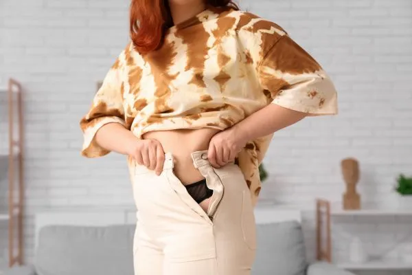 Image of woman trying to do her trousers up after pregnancy weight gain Birchills
