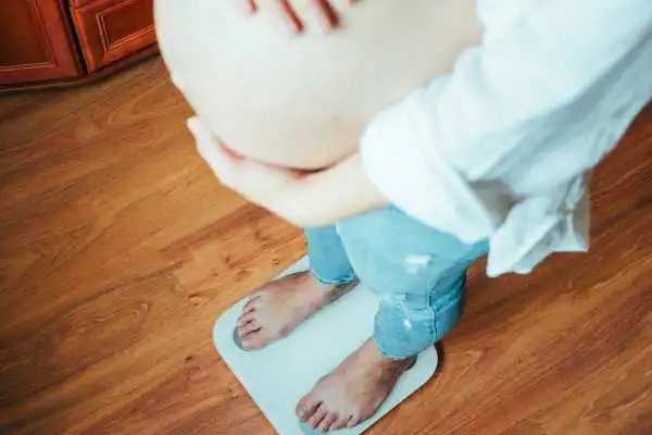Image of woman weighing herself and experiencing weight gain through pregnancy Birchills
